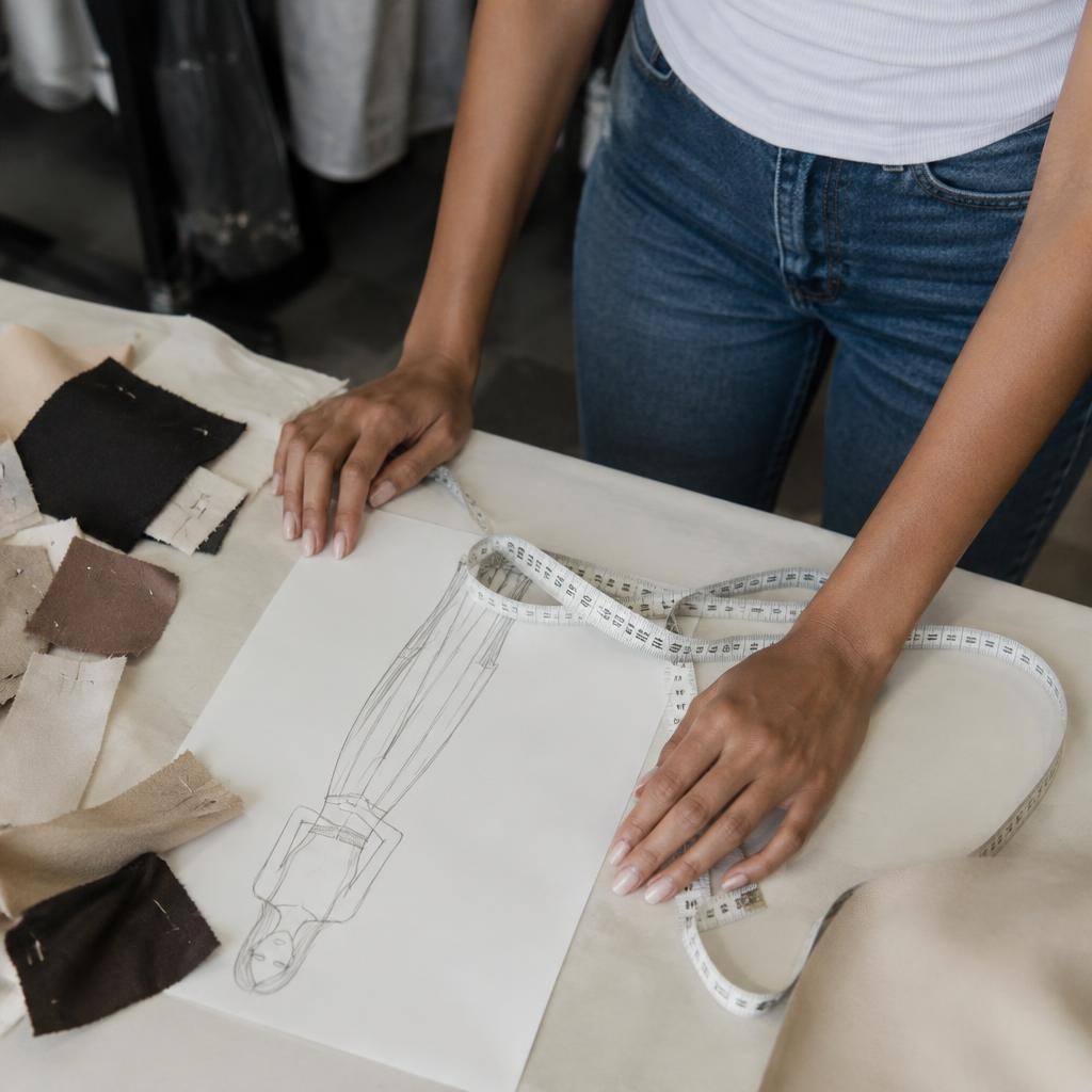 Manos de Noemí Castañeda sobre boceto y cinta métrica en fitting.